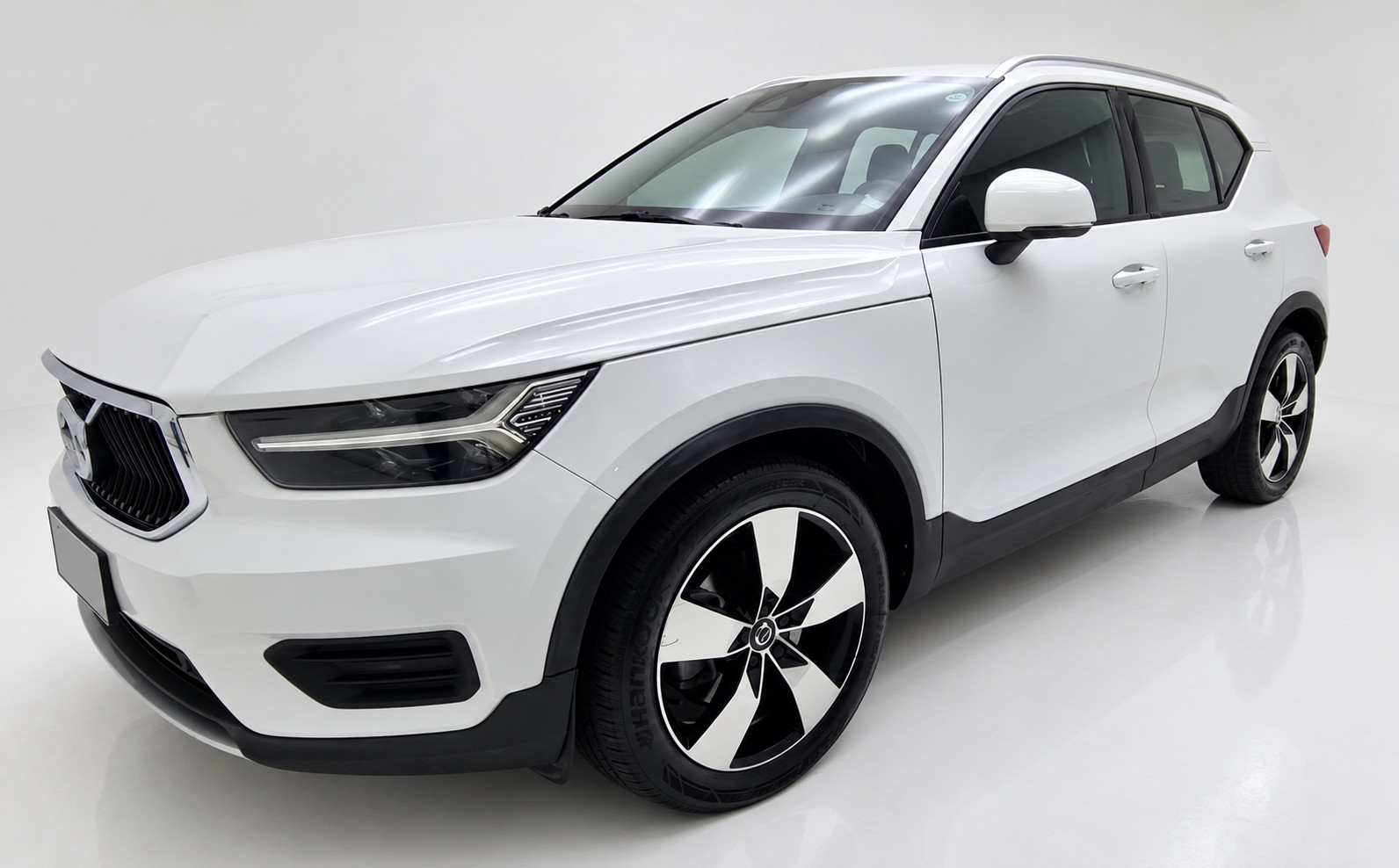 Volvo XC40 branco da VER BRASÍLIA: vista de frente e lateral em estúdio, com placa coberta